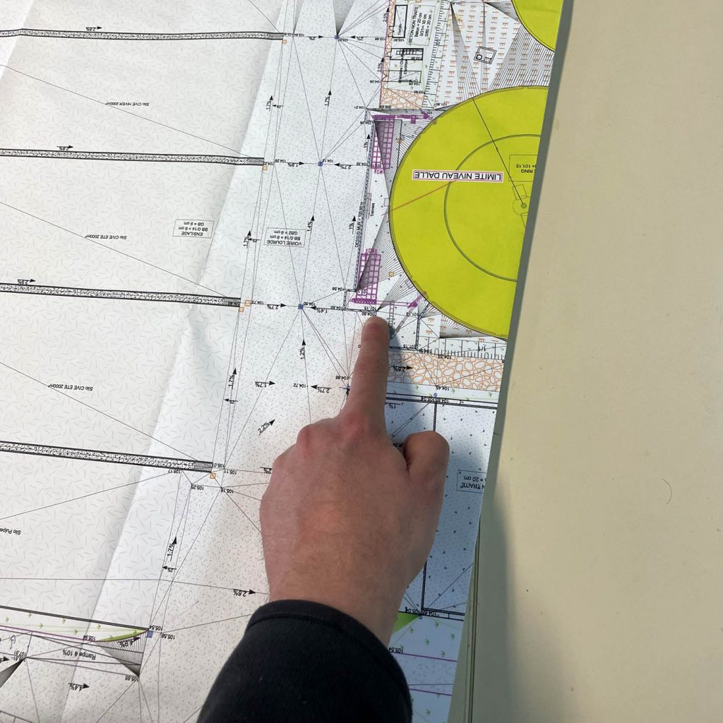doigt pointant un endroit sur un plan lors d'une réunion de chantier