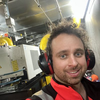 Homme d'une trentaine d'années dans conteneur de moteur biogaz avec un casque de protection auditif et une veste de chantier